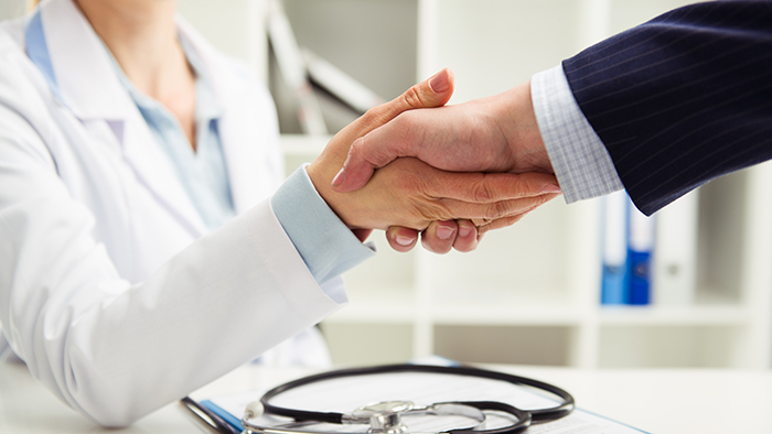 Woman doctor shaking hand with businessman in the office