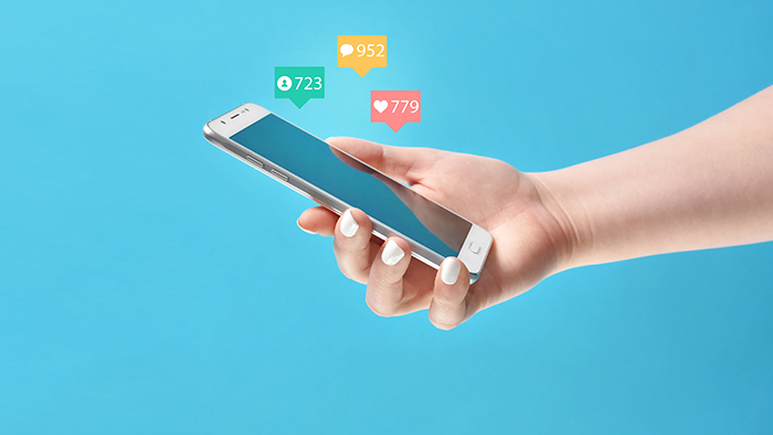 Girl’s hand holding smartphone in hand, surrounded with social m