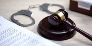 Gavel with handcuffs and legal document.